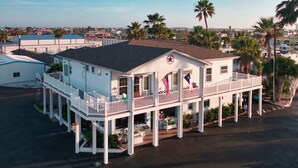 A white building with a balcony, a flag, and a sign indicating vacancy. - Tropic Island Resort (Port Aransas)
