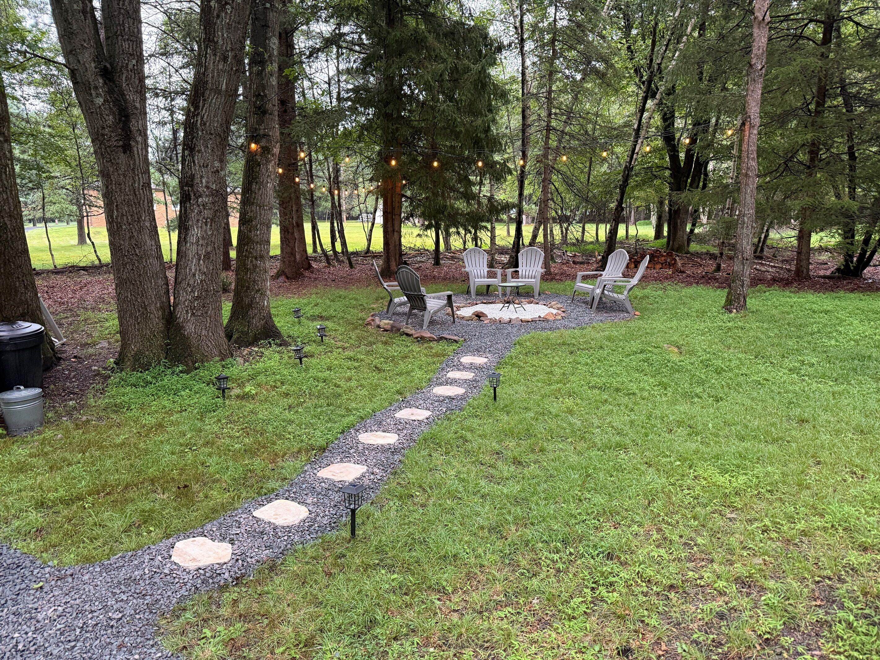 A garden area with a gravel path, outdoor seating, and trees.