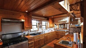 Cozinha rústica em estilo cabana, com fogão grande, pia dupla e armários de madeira.