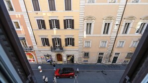 A street view with buildings, a red car, and people walking. - Cozy loft next to Spanish Steps (Roma)
