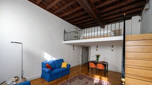 A spacious living area with a blue sofa, a patterned rug, and a dining table with chairs. - Cozy loft next to Spanish Steps (Roma)