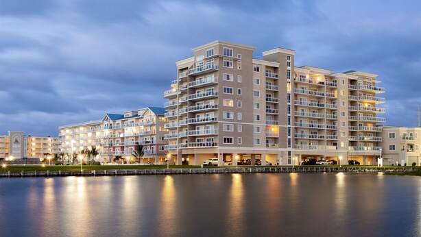 A multi-story hotel with balconies, a waterfront view, and a calm lake in the foreground.