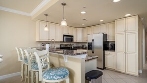 A kitchen with a central island, white cabinetry, and a dining area with four chairs.