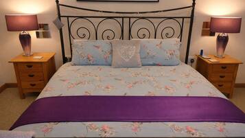 A bed with floral bedding, two bedside tables with lamps, and a headboard.