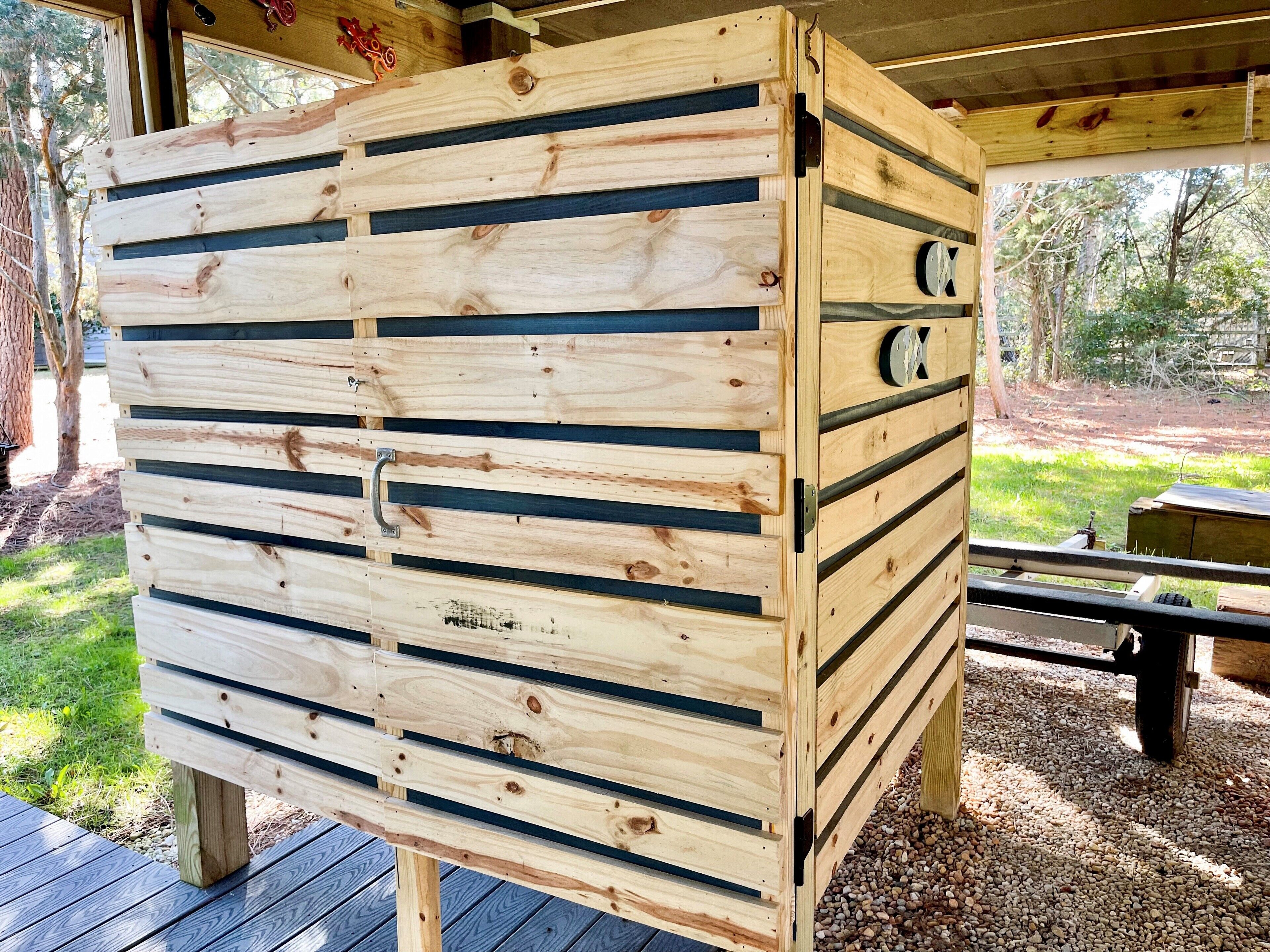 Une structure en bois composée de lattes horizontales, qui pourrait être un meuble de rangement ou un élément décoratif, située à l’extérieur, près d’une table de pique-nique.
