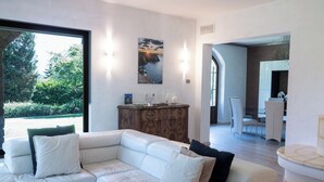 Una sala moderna con un sofá de cuero blanco, un armario de madera y un comedor al fondo.