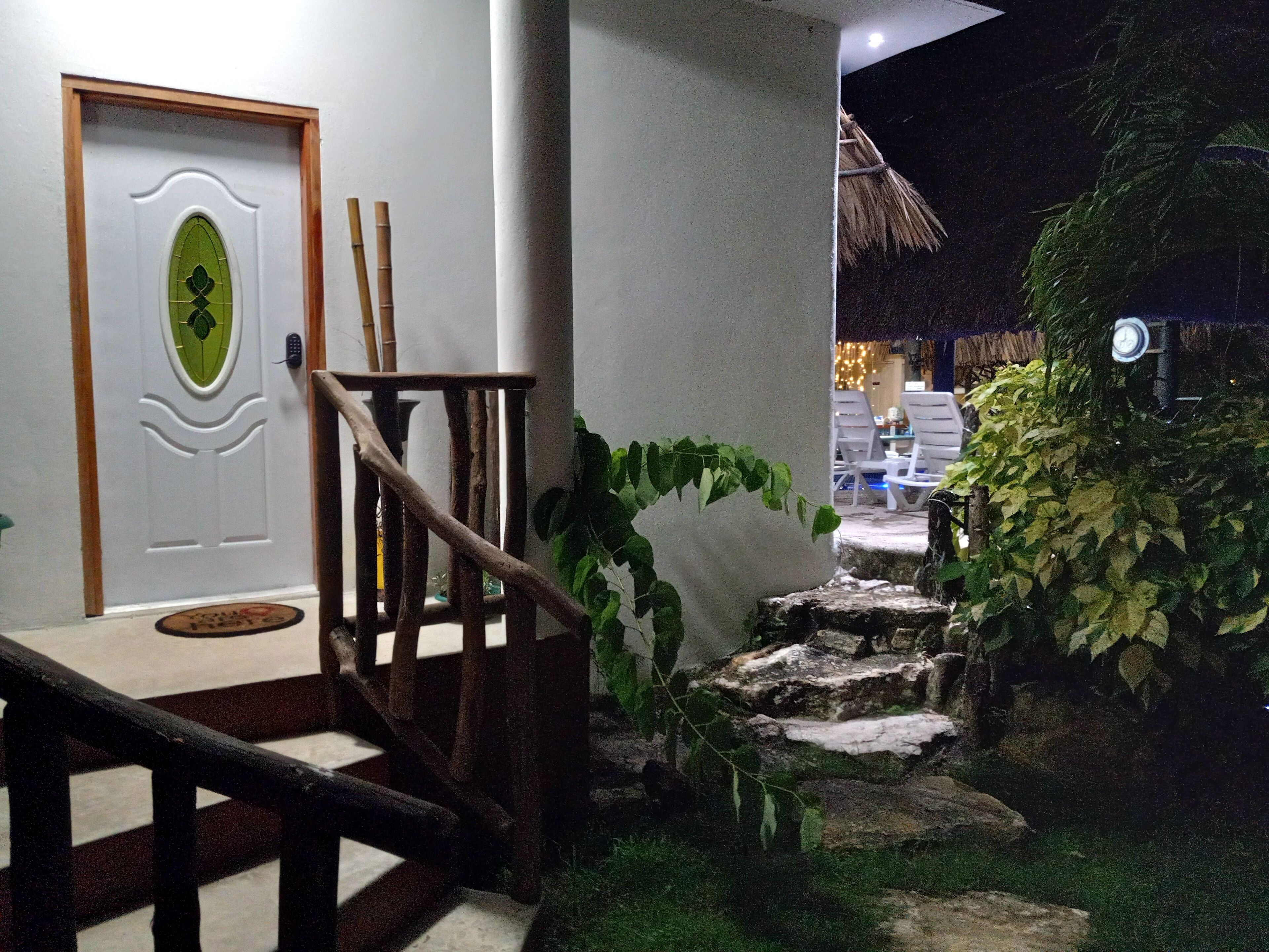 Uma escadaria com corrimão de madeira que leva a uma porta com painel decorativo verde.