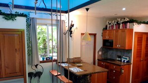 Une cuisine avec des meubles de rangement en bois, un îlot central et un luminaire suspendu.