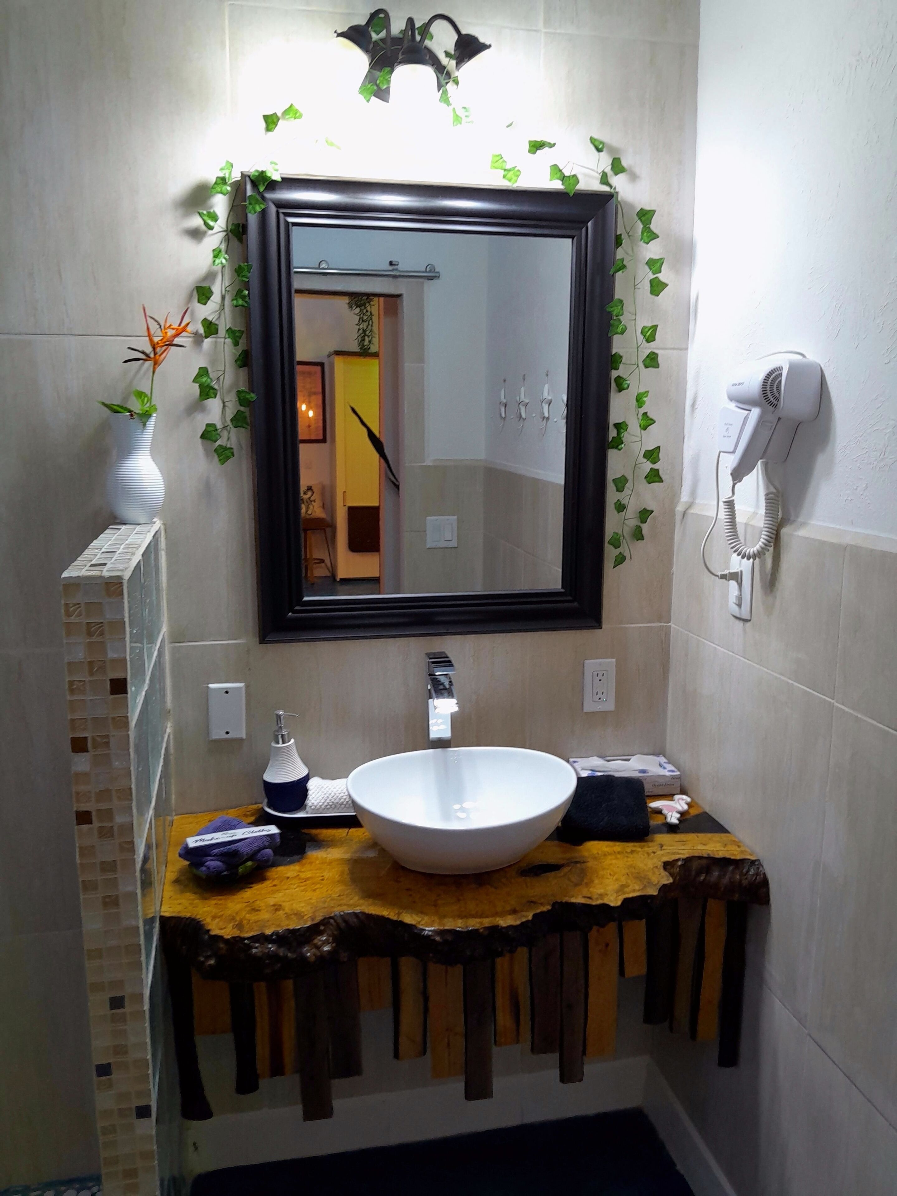Un bagno con un lavandino bianco, uno specchio e un asciugacapelli a parete.