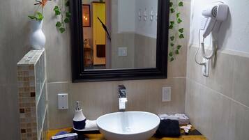 Un bagno con un lavandino bianco, uno specchio e un asciugacapelli a parete.