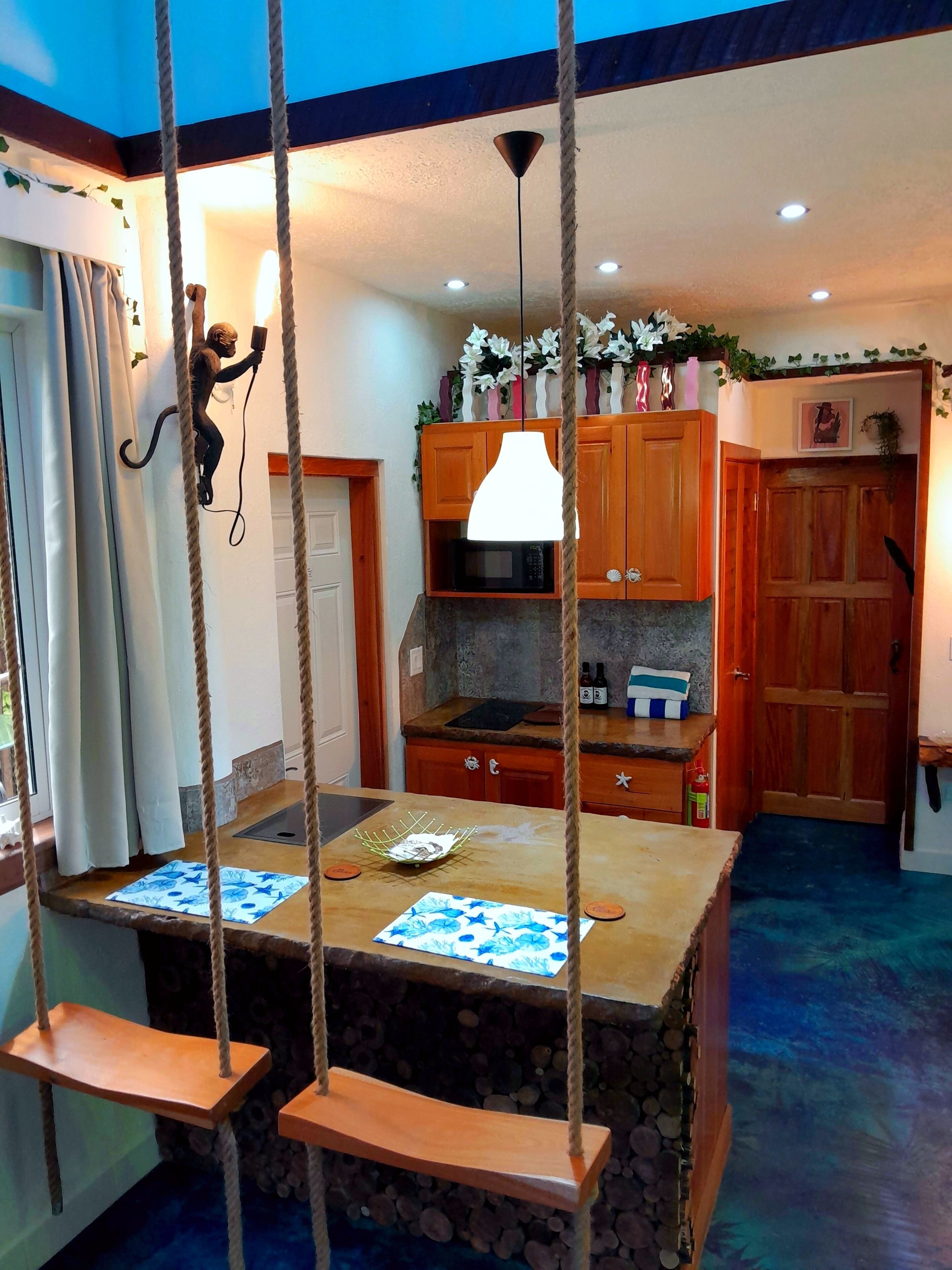 A kitchen with wooden cabinets, a hanging light fixture, and a stone countertop.