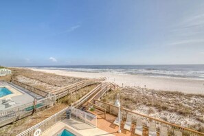 A beachside deck with a pool, wooden walkways, and lounge chairs.