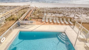 Ein Poolbereich mit Holzterrasse, Liegestühlen und Blick auf den Strand.