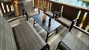 Un espace extérieur aménagé, abrité et doté d’un barbecue, de mobilier en osier et offrant une vue sur un lac et des montagnes.