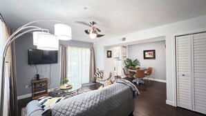 A compact living space with a bed, a TV, a dining area with a table and chairs, and a ceiling fan. - Near UF and SHANDS Hospital cozy spot (Gainesville)