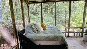 Un lit dans une cabane en bois avec vue sur une forêt.