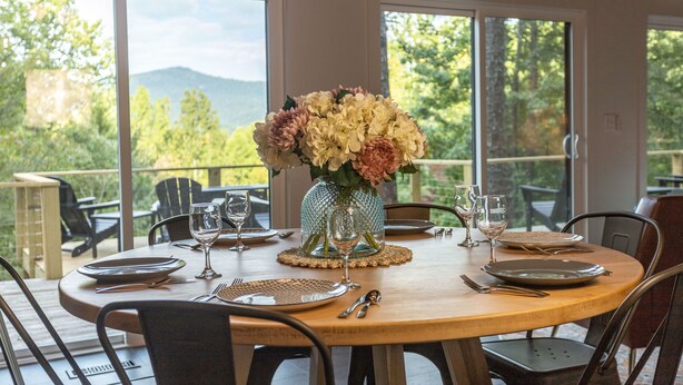 Une table à manger dressée pour quatre personnes, avec un vase de fleurs, des assiettes, des couverts et des verres.