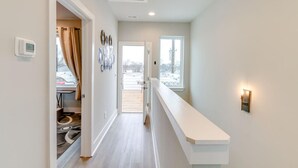 Un couloir moderne avec un banc blanc, un thermostat et une fenêtre donnant sur un beau paysage.
