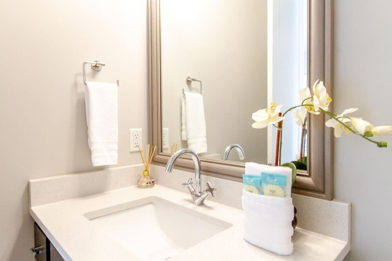 Une salle de bain avec un lavabo blanc, un miroir et un porte-serviettes.