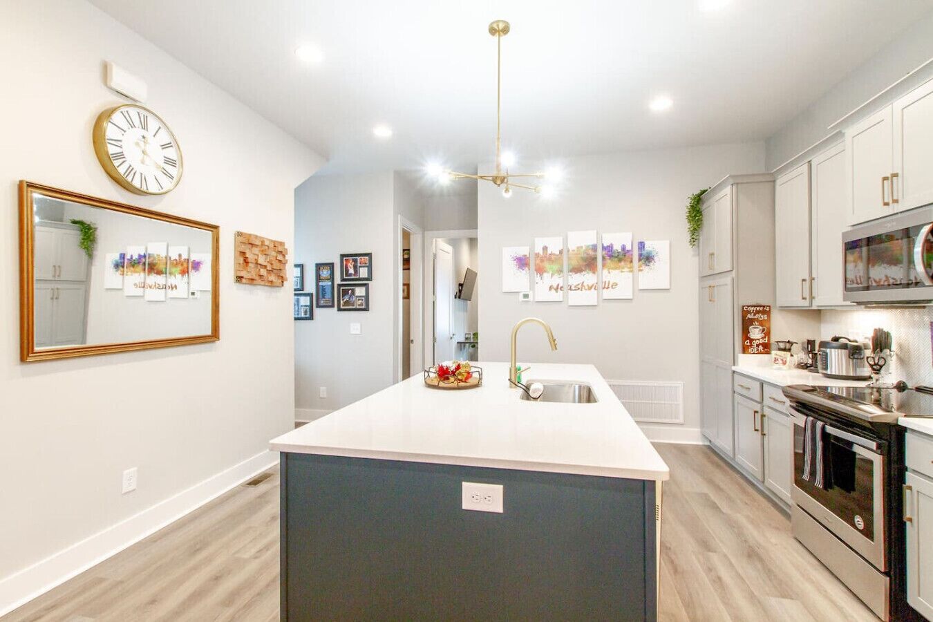 A modern kitchen with a central island, white cabinetry, and a large clock on the wall.