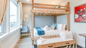 Une chambre avec un lit superposé, un bureau et une chaise, un attrape-rêves et un tableau abstrait rouge.
