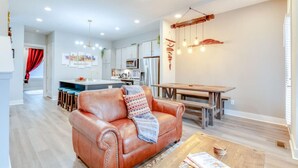 Une cuisine moderne avec des meubles blancs, un îlot central et un coin repas comprenant une table et des bancs en bois.