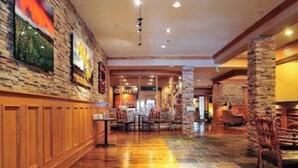 A spacious lobby with a wooden reception desk, stone pillars, and a tiled floor. - King Bed Condo at Cedar Breaks Lodge (Brian Head)