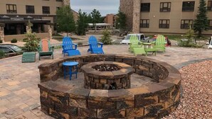 A circular stone fire pit with seating, surrounded by a paved patio area. - King Bed Condo at Cedar Breaks Lodge (Brian Head)