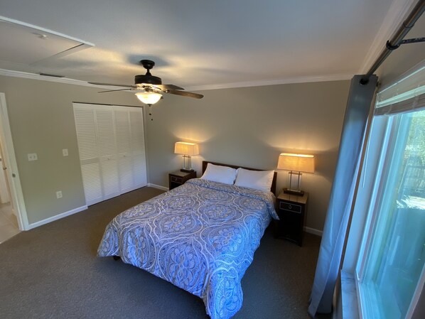 A bedroom with a bed, two bedside tables with lamps, a ceiling fan, a closet, and a window. - Vacation Rental on Siesta Key (Siesta Key)