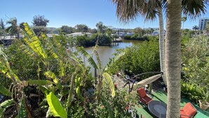 A patio area with a view of a body of water, surrounded by lush greenery and a palm tree. - Vacation Rental on Siesta Key (Siesta Key)