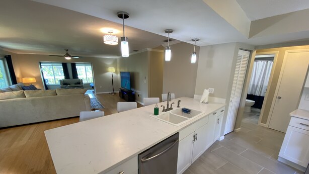 A modern kitchen with white cabinetry, stainless steel appliances, and pendant lighting. - Vacation Rental on Siesta Key (Siesta Key)