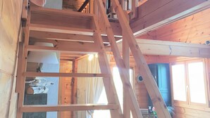 A wooden interior with a staircase, a ceiling fan, and a dining area with a table and chairs. - Wooden chalet with magnificent view (Neuviller-la-roche)
