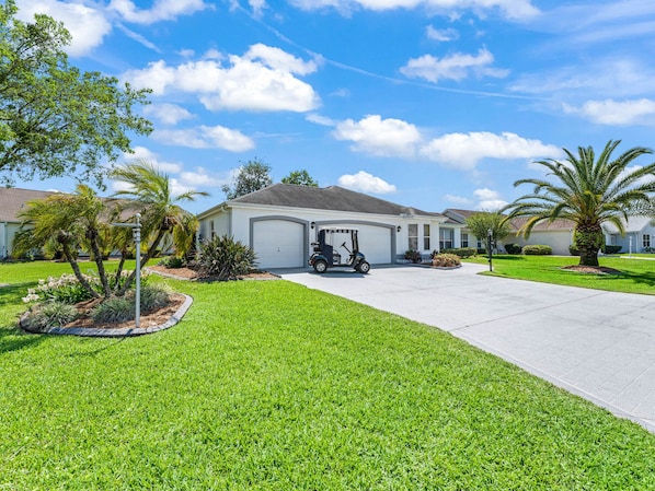 A residential area with a single-story house featuring a garage, a driveway, and a well-maintained lawn.