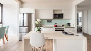 A modern kitchen with white cabinetry, stainless steel appliances, and a central island.