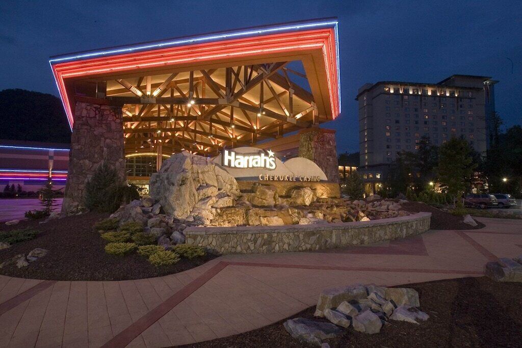 A Harrah's Cherokee Casino building with a prominent sign, stone pillars, and a well-lit entrance.