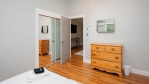 A bedroom with a wooden dresser, a mirror, and a door leading to another room. - Cheerful two bedroom cottage with Parisian patio! (Middletown)