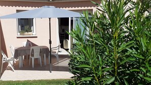 Un patio al aire libre con una mesa y sillas, una sombrilla grande y una planta en maceta.