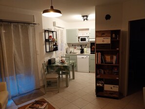 A compact living space with a dining area, kitchenette, and a bookshelf.