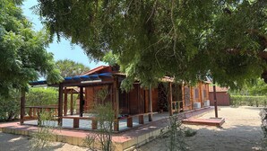 A wooden building with a covered porch, surrounded by trees and a sandy ground. - Suíte, Vila Alice, Luanda - Angola (Luanda)