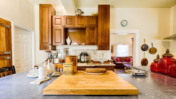 Een keuken met houten kastjes, een granieten aanrecht en een eethoek met een houten tafel.