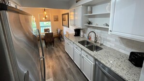 A modern kitchen with granite countertops, stainless steel appliances, and white cabinetry.