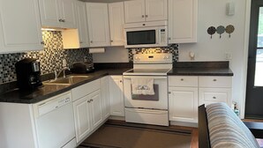 A compact kitchen with white cabinets, a microwave, a toaster, and a coffee maker. - Enjoy a Lake Huron view less than a minute walk to the beautiful sandy beach. (Au Gres)