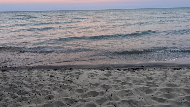 A beach with sand and gentle waves. - Enjoy a Lake Huron view less than a minute walk to the beautiful sandy beach. (Au Gres)