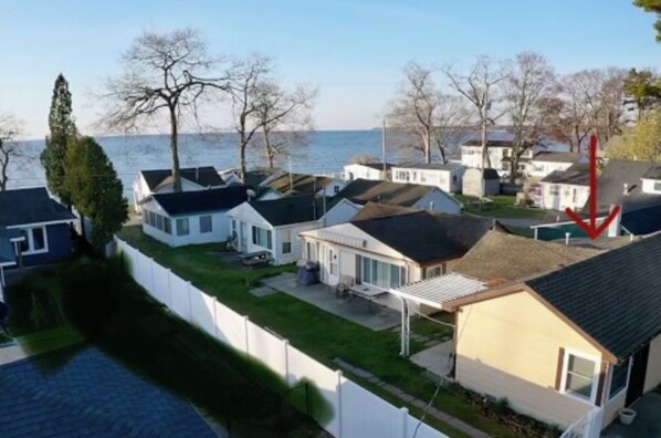A residential area with houses, a white fence, and a body of water in the background.