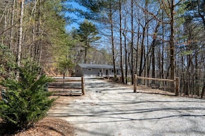 Escape to a secluded cabin surrounded by dense forest, offering a tranquil retreat with a simple, single-story structure and entryway.