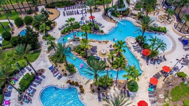 An aerial view of a resort with multiple swimming pools, palm trees, and sun loungers. - Fun Family Themed Resort home close to Disney. Regal Palms Resort  (Davenport)