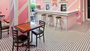A diner with a pink and white striped wall, a counter with a coffee machine, and a patterned floor. - Fun Family Themed Resort home close to Disney. Regal Palms Resort  (Davenport)