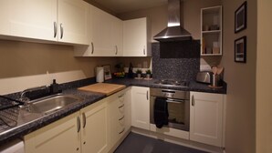 Eine moderne Küche mit weißen Schränken, einer Granit Arbeitsplatte, Edelstahlgeräten und einer schwarzen Spritzschutzwand.
