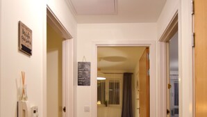 Ein Flur mit Teppichboden, der zu einem Schlafzimmer mit Bett und Nachttisch führt.