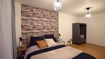 A bedroom with a bed, a nightstand, a lamp, a bookshelf, and a wall with a wooden plank design.